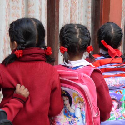 Students in Nepal wait patiently in a line for their Childcare volunteer Children line up with their backpacks outside their classroom in Nepal
